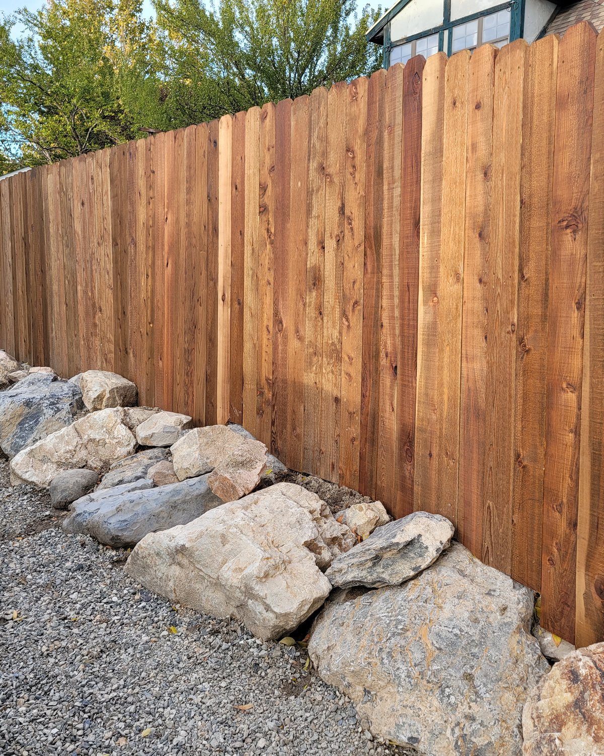 Cedar privacy fence with river rock landscape border
